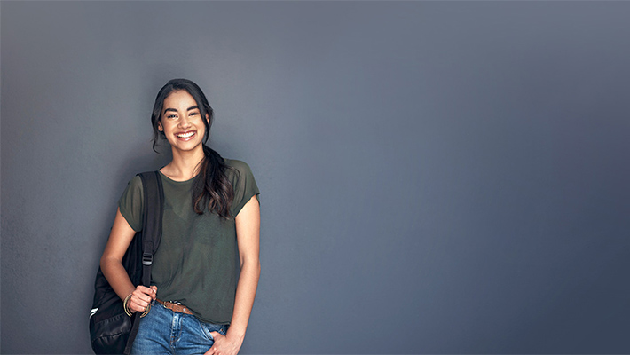 Portrait of a young cheerful woman carrying a bag and looking at the camera