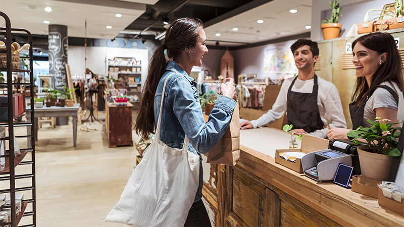 Smiling lady shopping in a retail store and talking with a shop worker