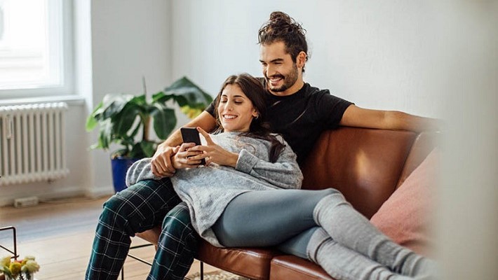Smiling couple sitting on the couch and enjoying a clip on the phone