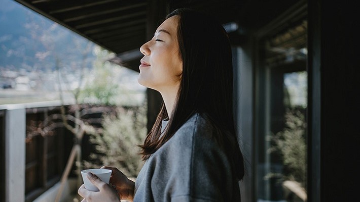 Woman enjoying the morning sunrise with a cup of tea