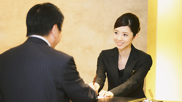 Smiling front desk lady helping a hotel guest