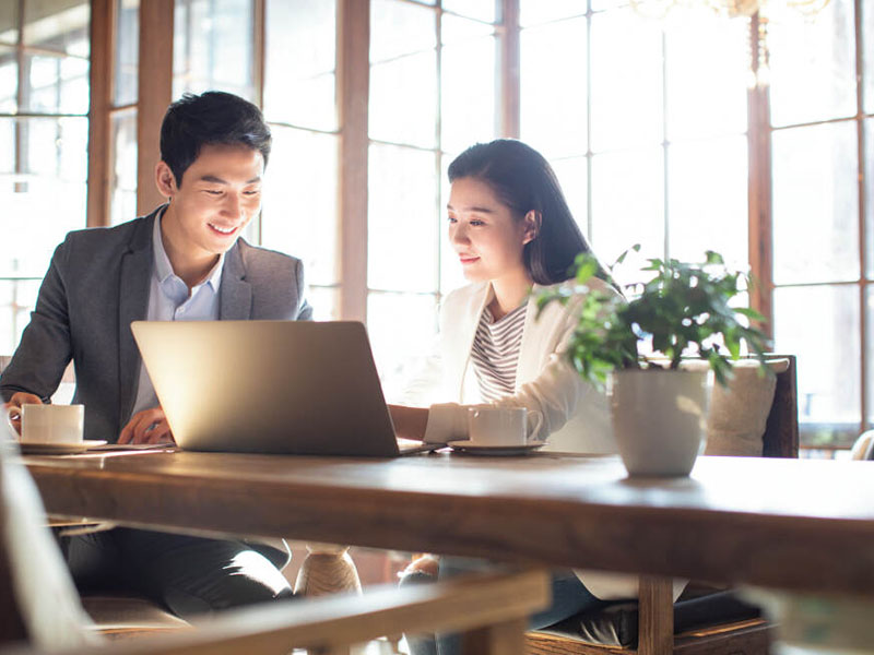 Two employees discussing something while looking at the laptop inside the office