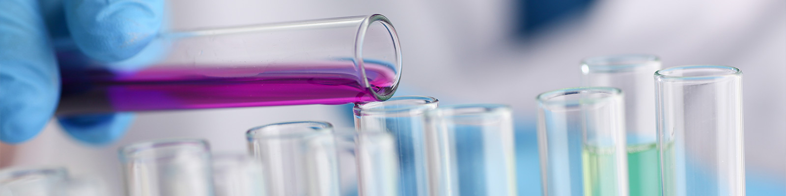 Medical researcher adding a chemical liquid to a test tube during their research in a medical laboratory