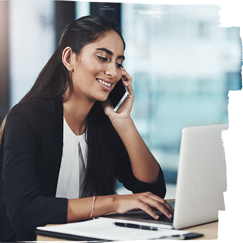 Young woman talking on the mobile phone while using her laptop 