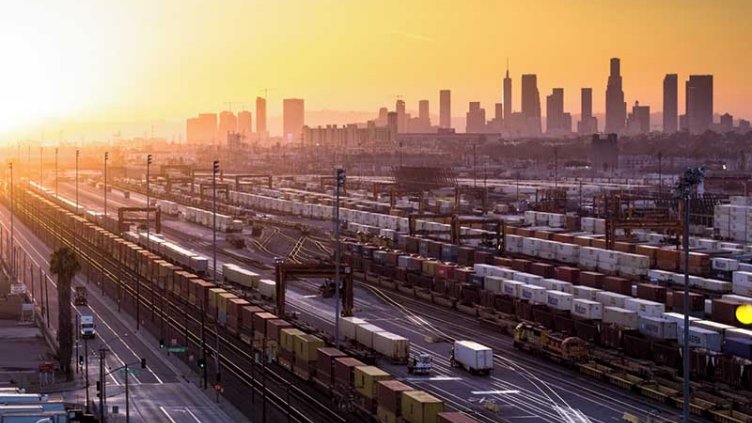 This is a sunset aerial shot of an industrial area made up of factories and warehouses surrounded by the City of LA.