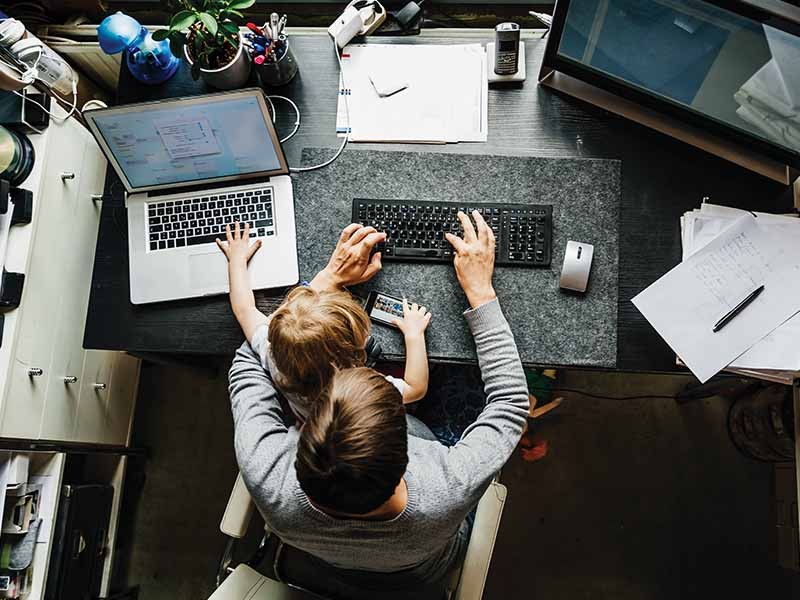 Young mother working from home with a child on her lap