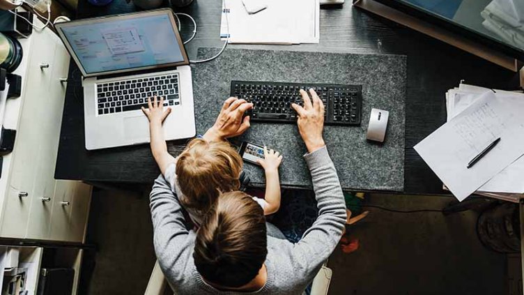 Young mother working from home with a child on her lap