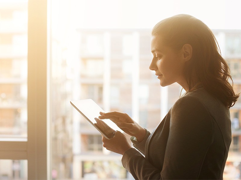 A young woman using a tablet near a window at an office