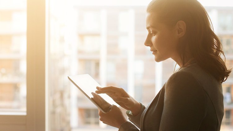 A young woman using a tablet near a window at an office