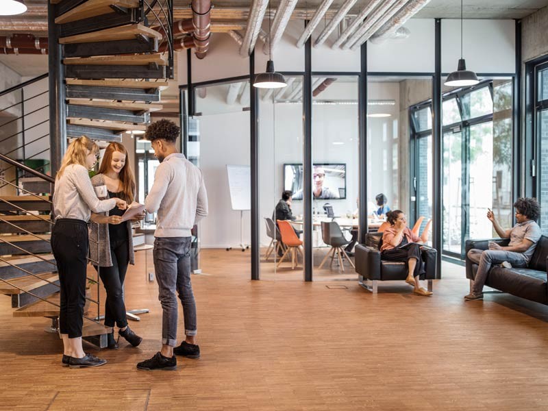 employees are standing speaking in office space