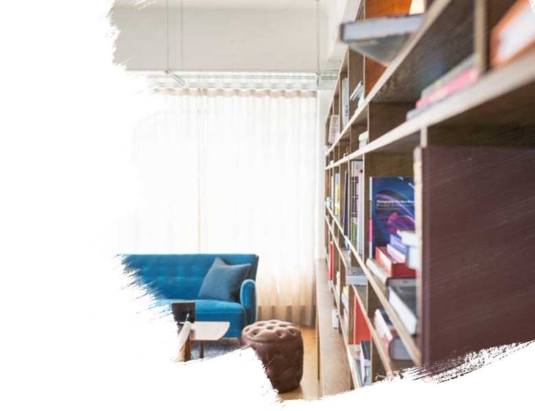 Blurred view of bookselves in a living room wth blue couch