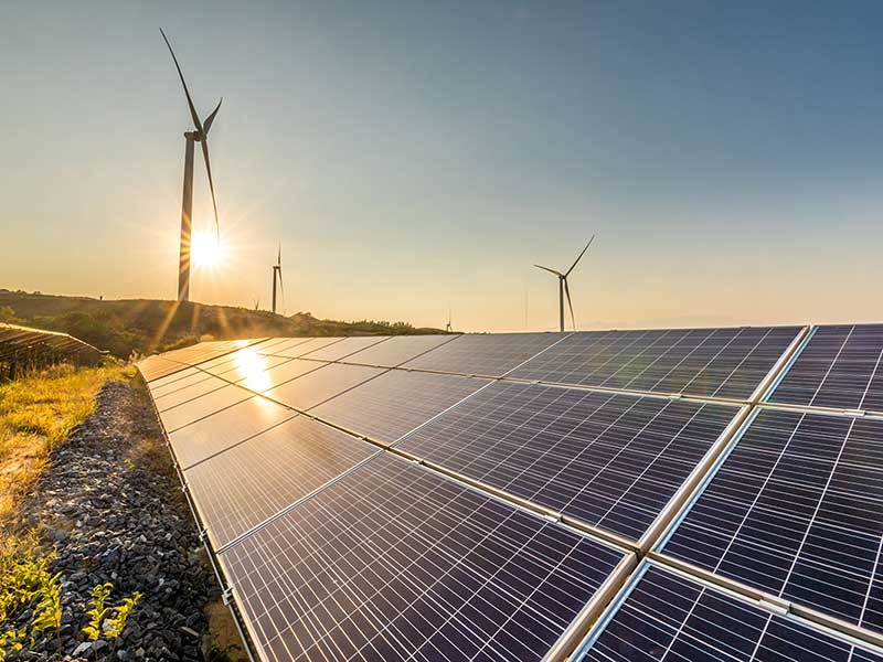 View of solar panel and wind turbines during sunrise